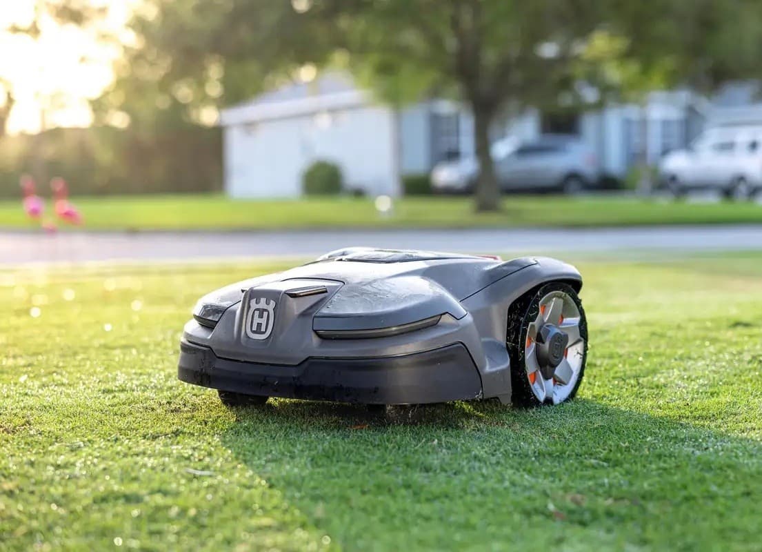 Husqvarna Automower robotic mower cutting a residential lawn at golden hour
